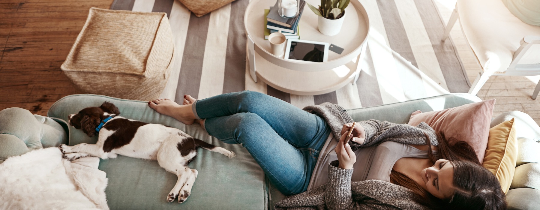 lifestyle image of a woman laying beside her pet on a couch